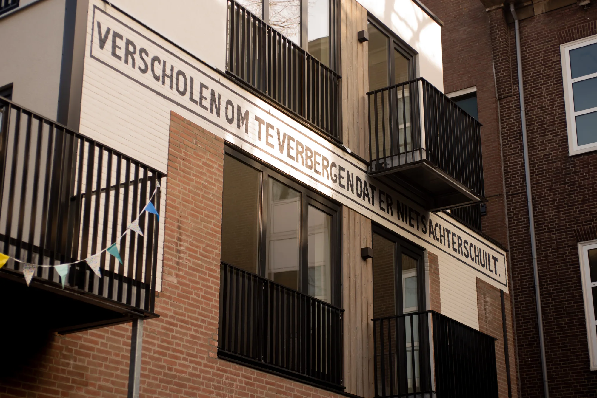Woongebouw in Roosendaal met een tekst in zwarte letters geschilderd op de witte gevel langs de balkons