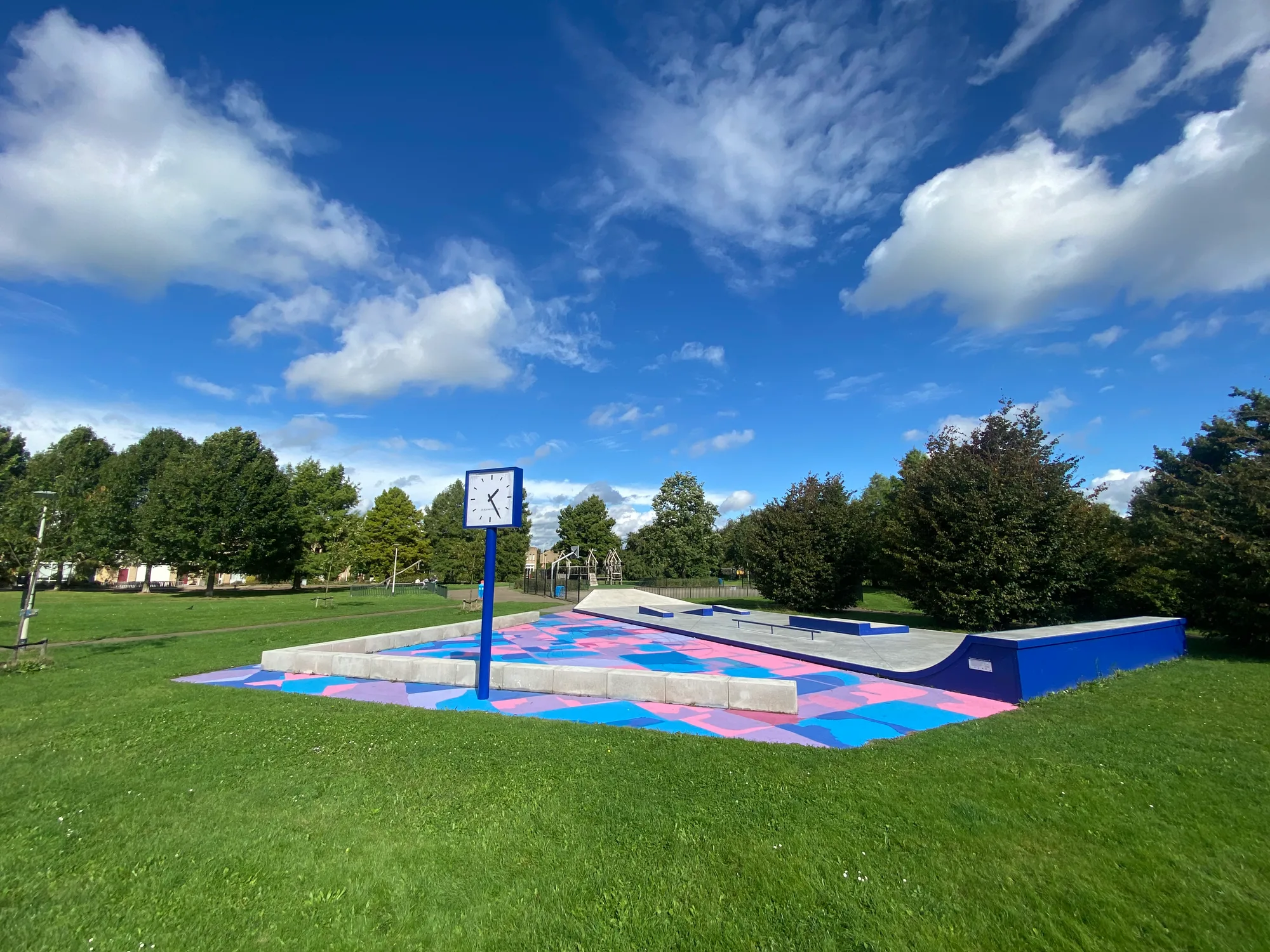 De blauwe speeltuin in Tolberg, Roosendaal: skatepark met vloerschildering in roze, paars en blauw onder een blauwe lucht