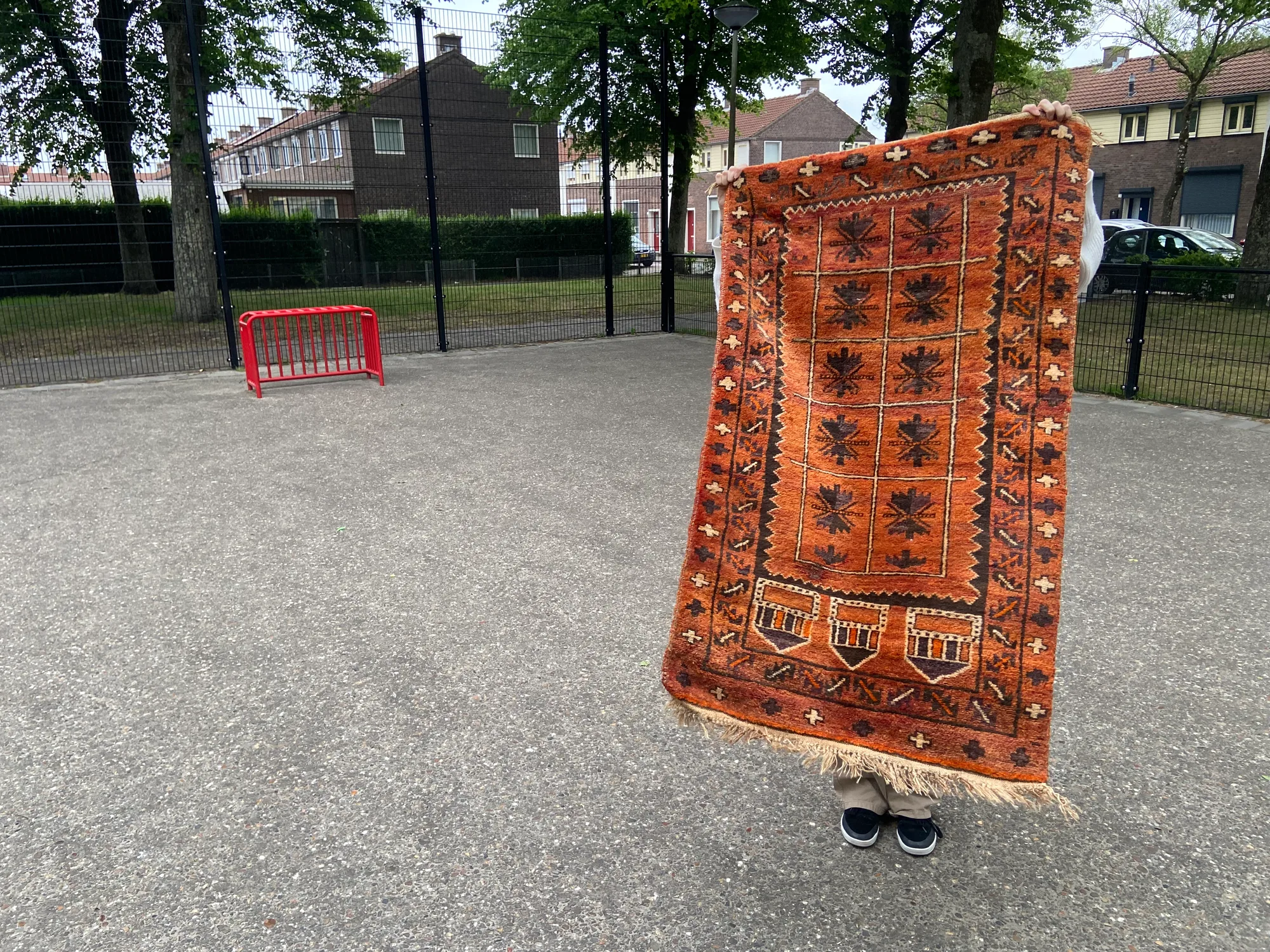 Bewoner houdt een oosters kleed omhoog op het pleintje aan de Wattstraat