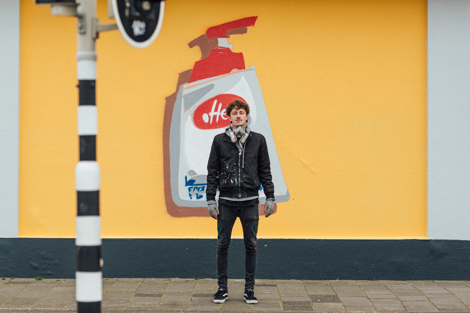 Tom Onrust voor een gele muurschildering van een Delfts blauwe kruik in Breda